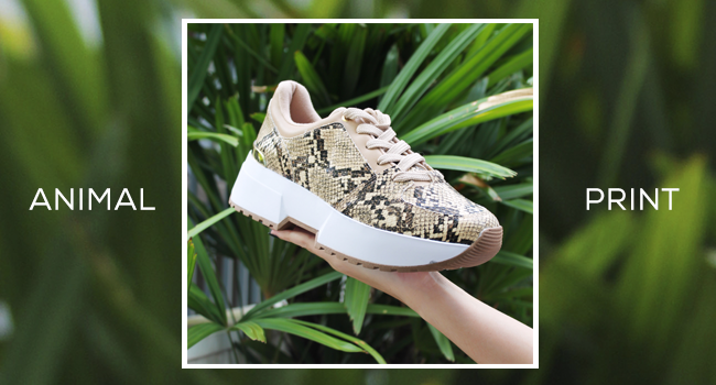 O post, com fundo verde desfocado, mostra um dad sneaker com animal print